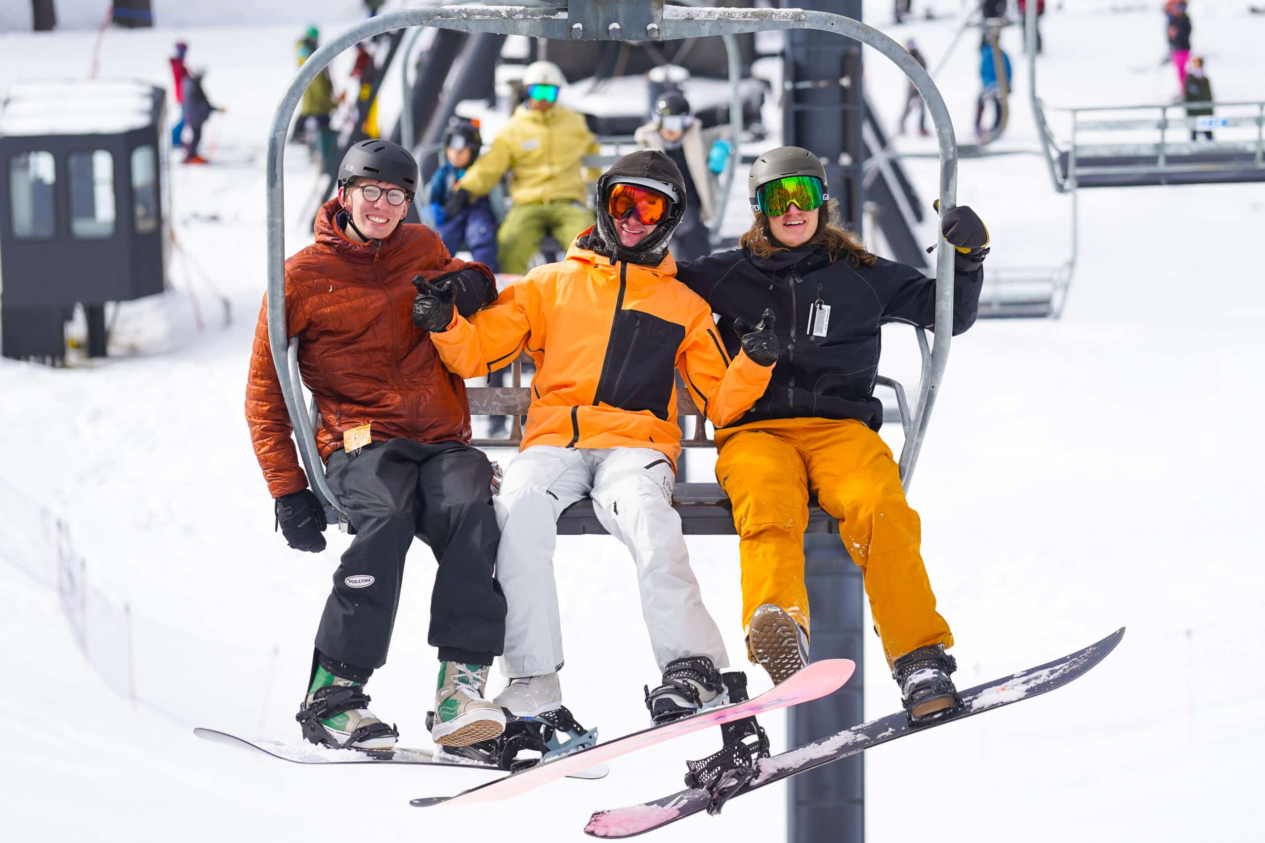 three snowboarders sitting on a chairlift