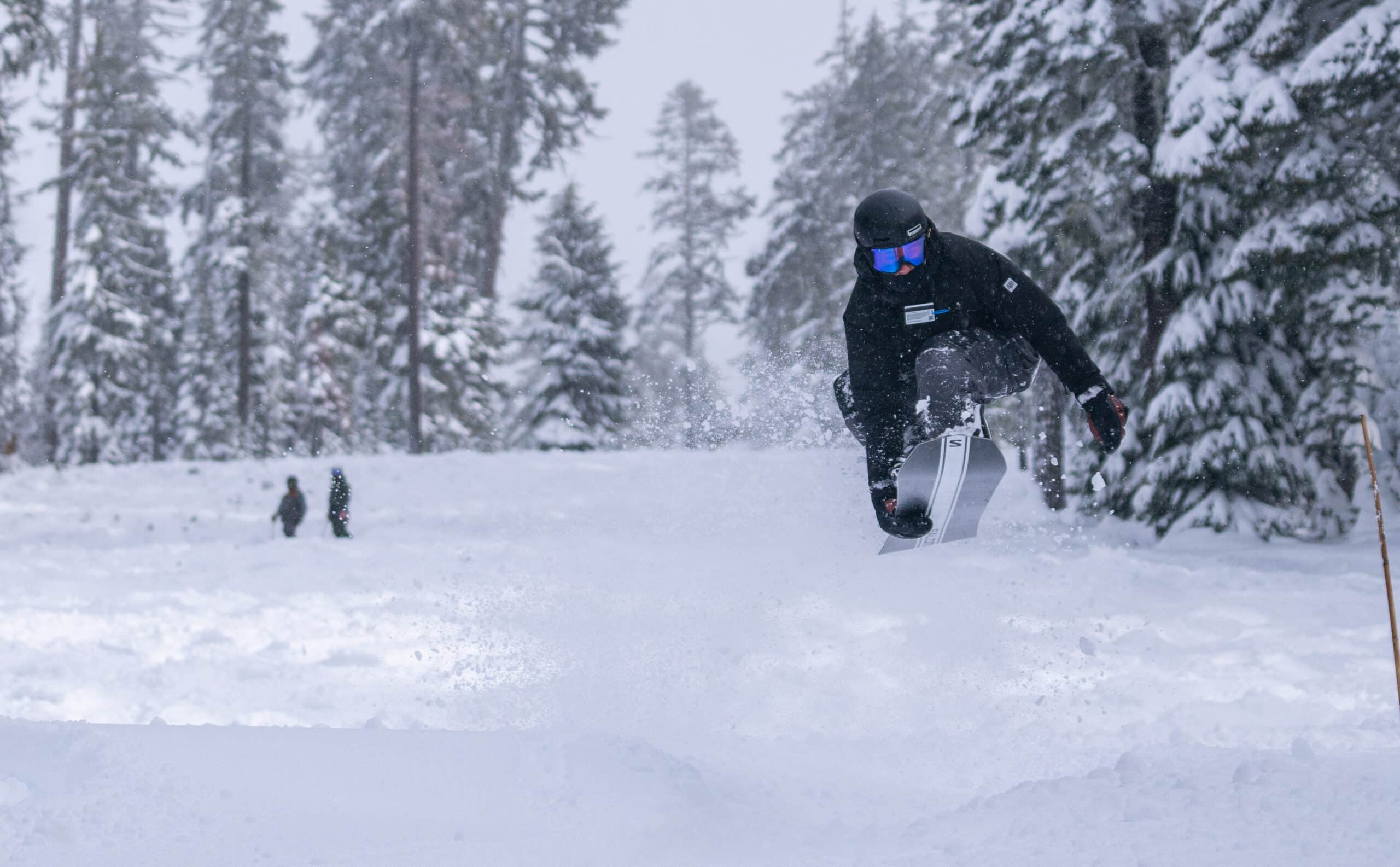 person jumping through powder on a snowboard