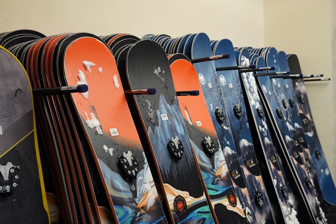 Dozens of snowboards leaning against wall.